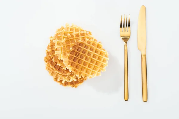 Blick von oben auf goldene Gabel und Messer bei Waffeln auf Weiß — Stockfoto