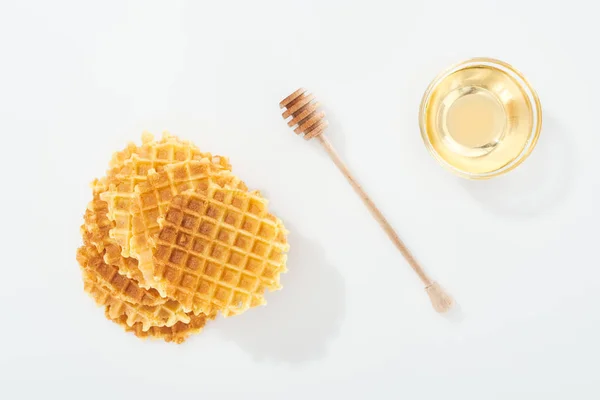 Draufsicht auf Waffeln in der Nähe von Holzdipper und Schüssel mit Honig auf Weiß — Stockfoto