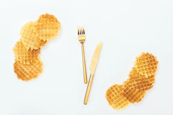 Draufsicht auf Waffeln und goldenes Besteck in der Mitte isoliert auf weiß — Stockfoto