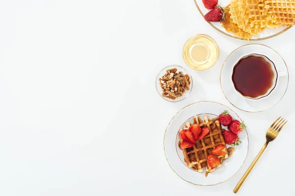 Vista superior de fresas, gofres y té sobre blanco - foto de stock