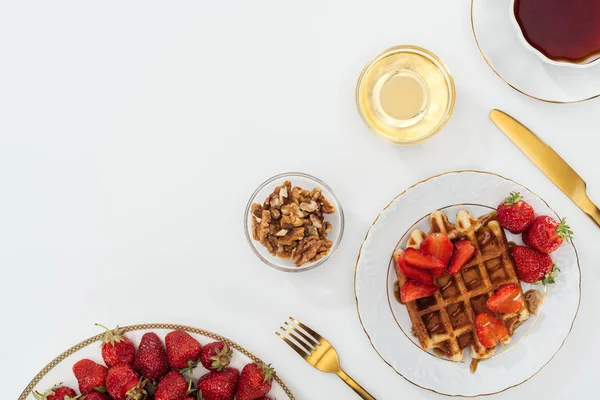 Vue de dessus des fraises sur assiette près des bols sur blanc — Photo de stock