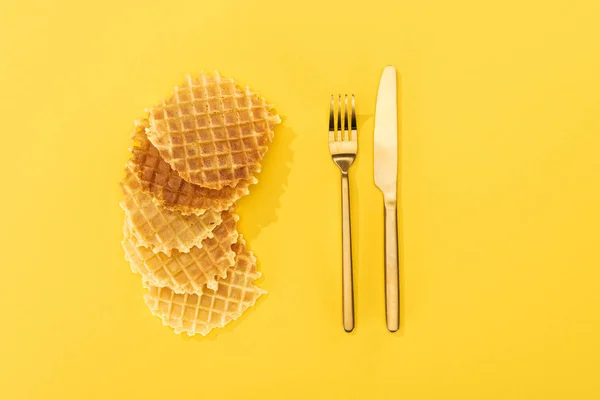 Top view of crispy and delicious waffles near cutlery on yellow — Stock Photo