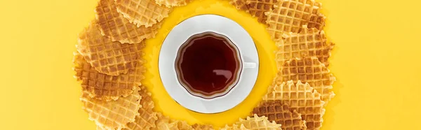 Panoramic shot of waffles in circle with cup of tea in middle on yellow — Stock Photo