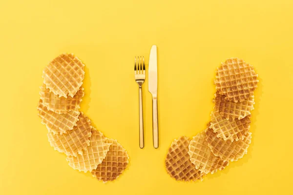 Blick von oben auf knusprige und leckere Waffeln mit Besteck in der Mitte isoliert auf gelb — Stockfoto