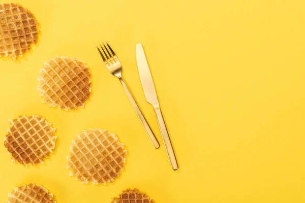 Top view of waffles near cutlery in middle isolated on yellow — Stock Photo