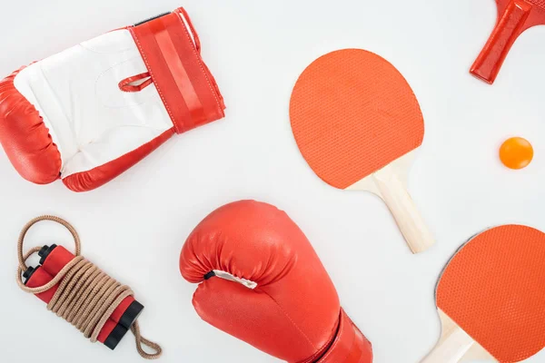 Top view of boxing gloves near red ping pong rackets and skipping rope isolated on white — Stock Photo