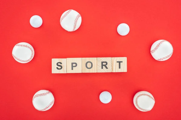 Letras desportivas em cubos de madeira perto de softballs isolado em vermelho — Fotografia de Stock