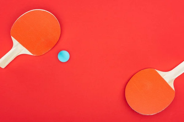 Top view of blue ping pong ball near rackets isolated on red — Stock Photo