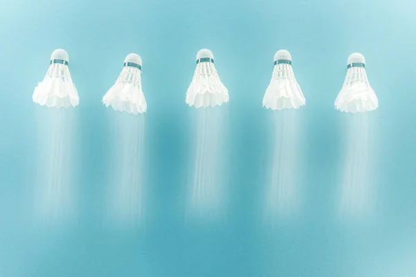 Motion blur of white shuttlecocks with feathers flying on blue — Stock Photo