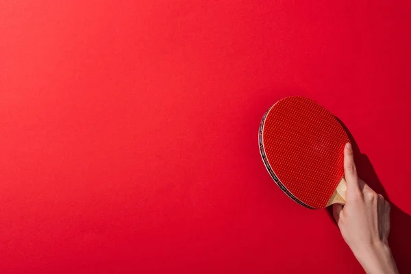 Cropped view of woman holding table tennis racket on red — Stock Photo