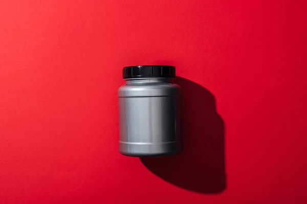 Top view of grey plastic jar with protein on red — Stock Photo