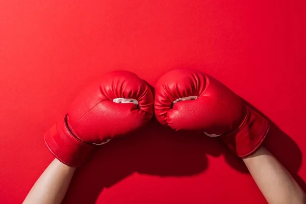 Обрезанный вид женщины в паре боксерских перчаток на красном — стоковое фото