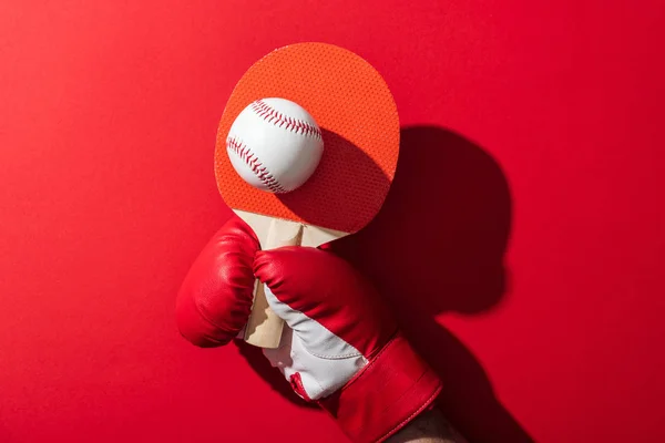 Cropped view of woman in boxing glove holding tennis racket and baseball on red — Stock Photo
