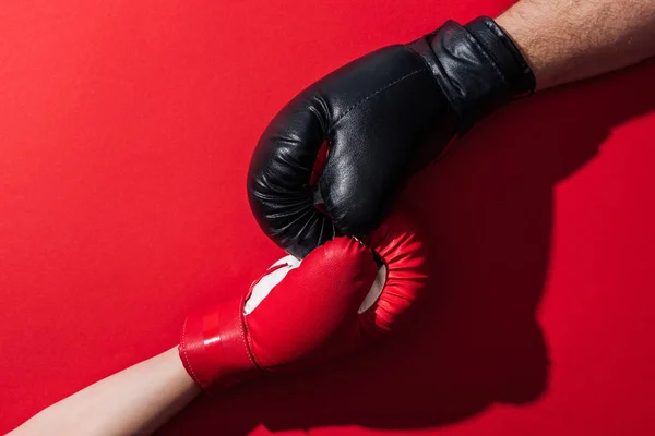 Обрезанный вид мужчины и женщины в боксёрских перчатках на красном — стоковое фото