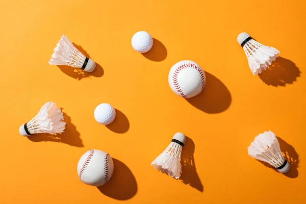 Top view of shuttlecocks with feathers near softballs and golf balls on yellow — Stock Photo