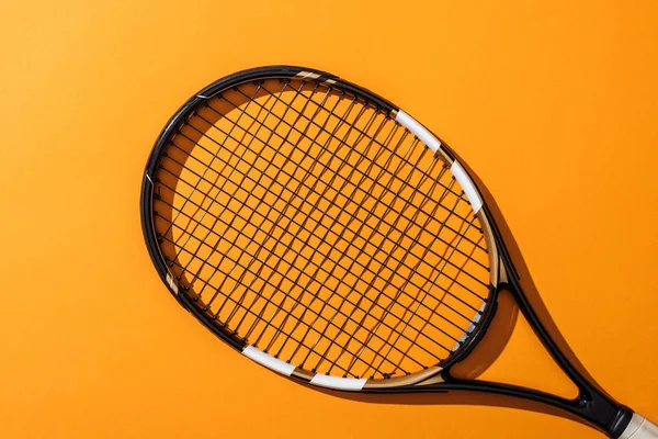 Top view of black tennis racket on yellow — Stock Photo