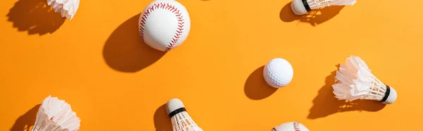 Panoramic shot of shuttlecocks with feathers near softball and golf ball on yellow — Stock Photo