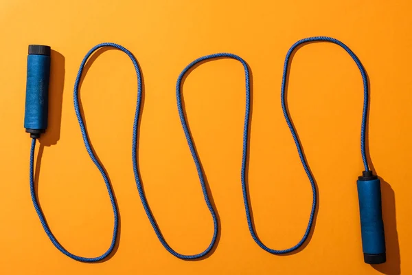 Top view of blue and waved skipping rope on yellow — Stock Photo