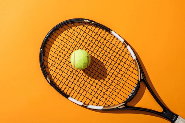 Vista superior da raquete de tênis perto de bola de tênis verde no amarelo — Fotografia de Stock