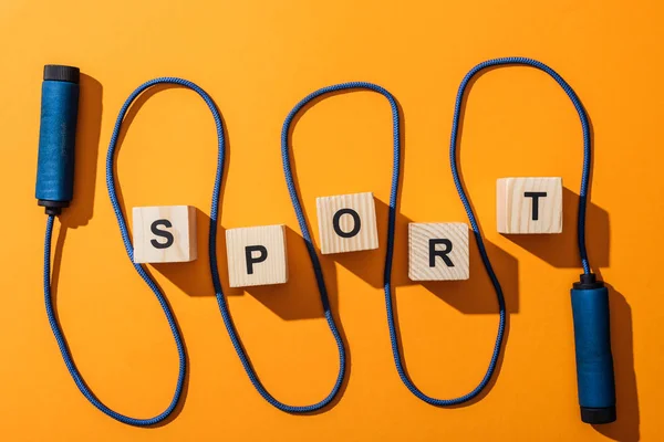 Top view of jumping rope near wooden cubes with sport lettering on yellow — Stock Photo