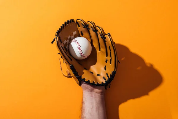 Vista recortada del hombre sosteniendo softbol en guante de béisbol marrón en amarillo - foto de stock