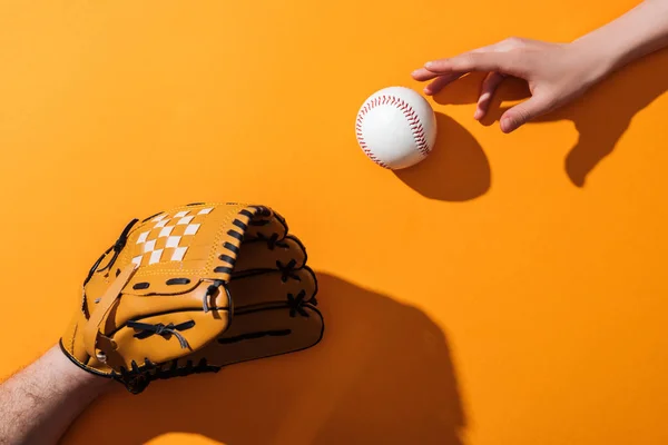 Cropped view of man in brown baseball glove near softball and woman on yellow — Stock Photo