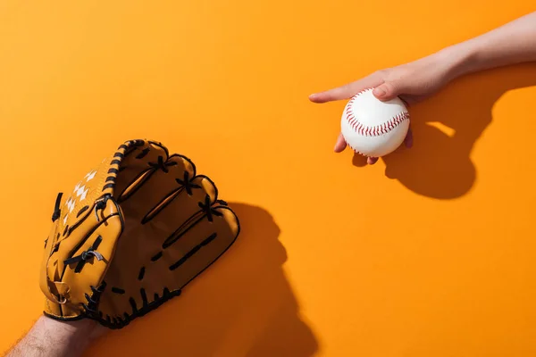 Vista recortada del hombre en guante de béisbol marrón cerca de la mujer sosteniendo softbol en amarillo - foto de stock