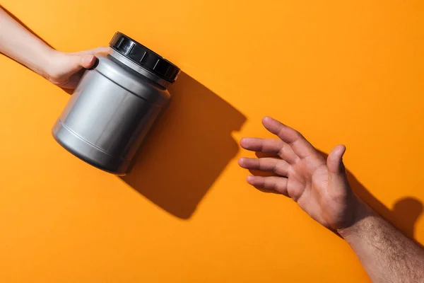 Cropped view of woman holding grey jar near man on yellow — Stock Photo