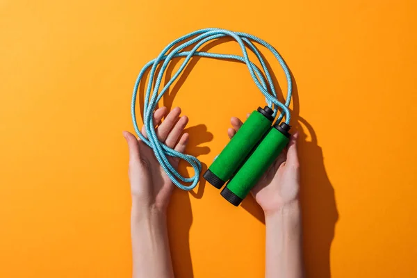 Cropped view of sportive woman holding jumping rope on yellow — Stock Photo