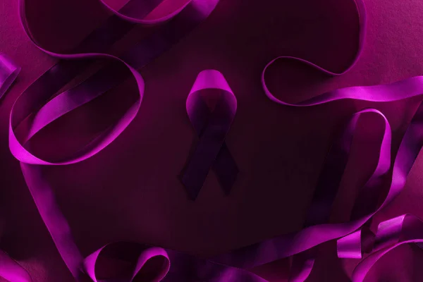 Top view of purple ribbon rounded by other ribbons in shadow — Stock Photo