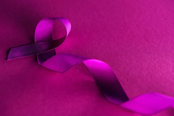 Purple ribbon on pink background with shadow, violence concept — Stock Photo