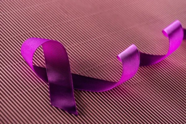 Purple ribbon on pink texture background in shadow — Stock Photo