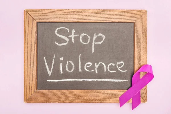 Top view of purple ribbon on blackboard with inscription isolated on pink — Stock Photo