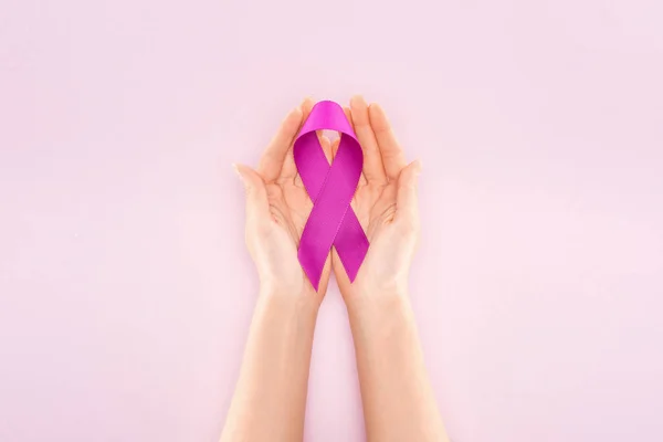 Cropped view of purple ribbon on hands of woman isolated on light pink — Stock Photo