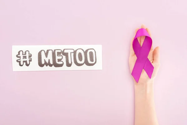 Abgeschnittene Ansicht von lila Awareness Ribbon auf der Hand einer Frau in Papiernähe mit Hashtag me too isolated on pink — Stockfoto