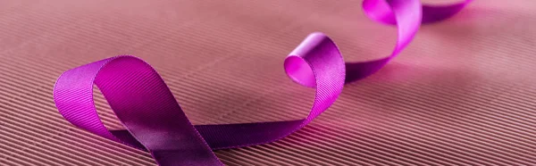 Panoramic shot of purple ribbon on pink texture background in shadow, violence concept — Stock Photo