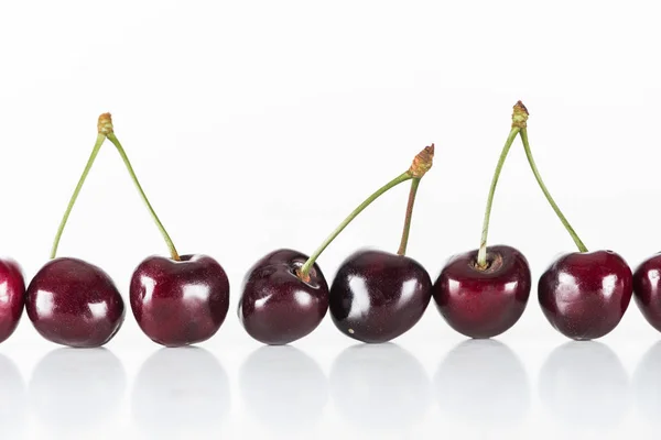 Cerezas rojas, frescas, enteras y dulces sobre fondo blanco con espacio para copiar - foto de stock