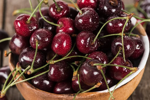 Red, fresh, whole and ripe cherries covered with droplets on bowl on wooden table — Stock Photo