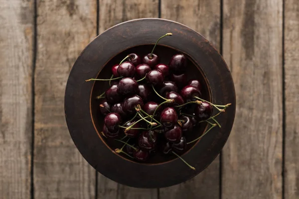 Top view of red, fresh, whole and ripe cherries on bowl on wooden surface — Stock Photo