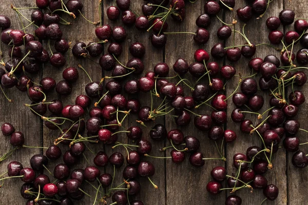 Vista superior de cerezas rojas, frescas, enteras y lavadas en la superficie de madera - foto de stock