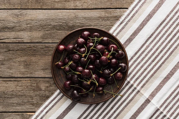 Вид сверху на свежие, цельные и спелые вишни, покрытые каплями воды на тарелке — стоковое фото