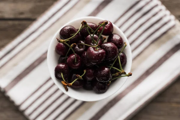 Top view of fresh, whole and ripe cherries covered with droplets on bowl — Stock Photo