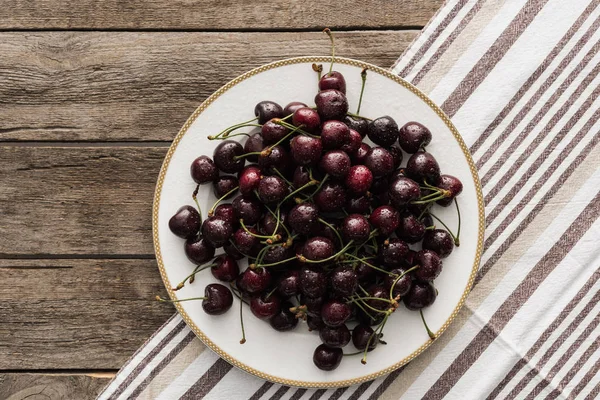 Top view of fresh, whole and ripe cherries covered with droplets on plate — Stock Photo