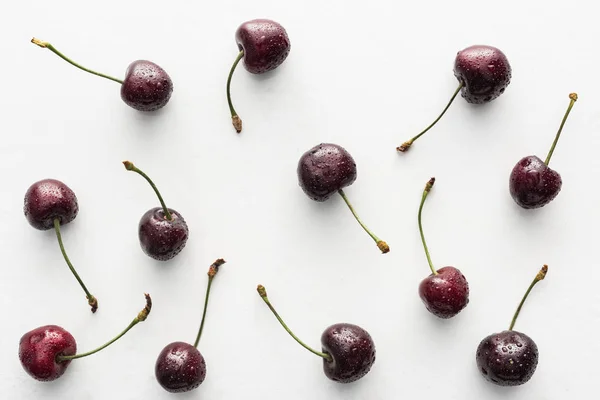 Top view of fresh, whole and ripe cherries covered with water drops on white background — Stock Photo