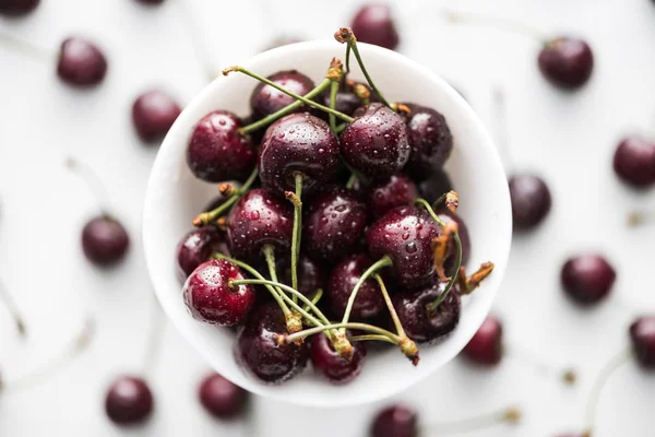 Vue de dessus des cerises rouges, entières et mûres recouvertes de gouttes d'eau dans un bol — Photo de stock