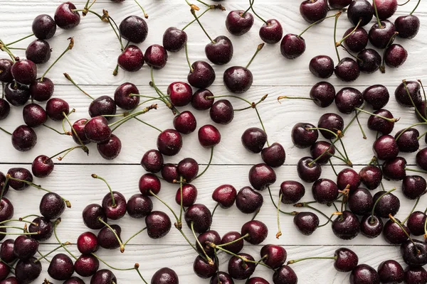 Vue de dessus des cerises fraîches, sucrées et mûres recouvertes de gouttelettes sur fond en bois — Photo de stock