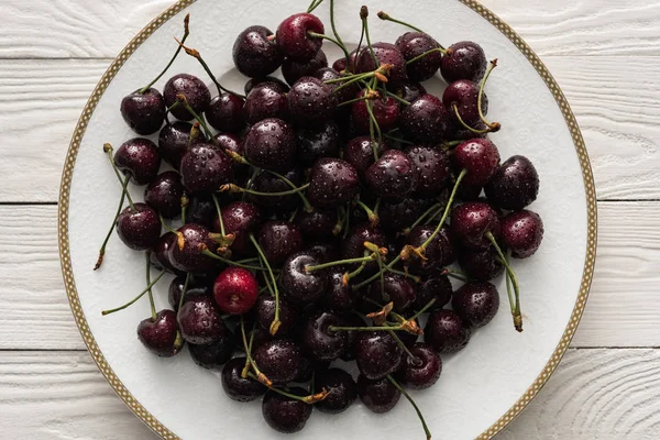 Top view of fresh, sweet and ripe cherries covered with droplets on white plate — Stock Photo