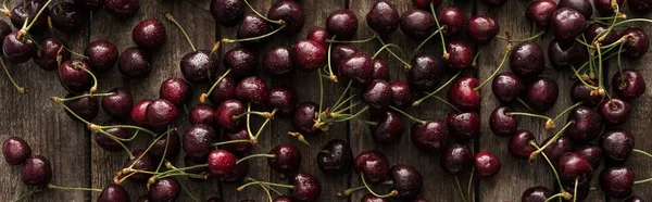 Panoramic shot of fresh, sweet, red and ripe cherries covered with water drops on wooden table — Stock Photo
