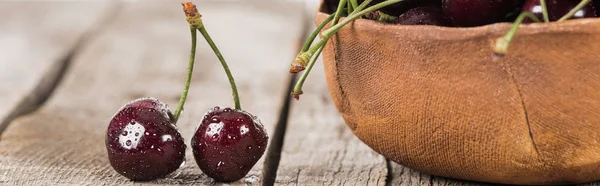 Panoramic shot of fresh, sweet, red and ripe cherries covered with water drops on wooden table — Stock Photo