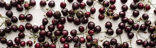 Plano panorámico de cerezas frescas, dulces, rojas y maduras con gotitas sobre mesa de madera - foto de stock